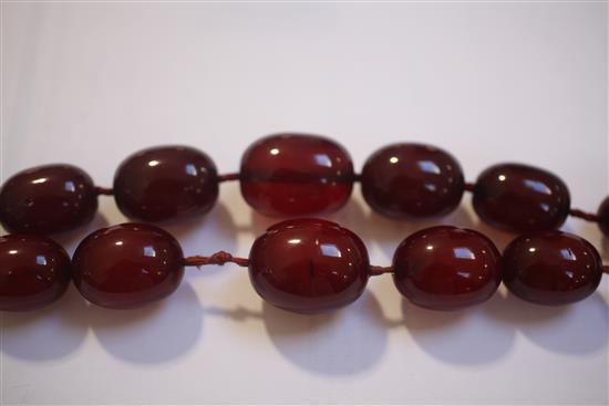 Two single strand red simulated amber bead necklaces, largest 158cm.